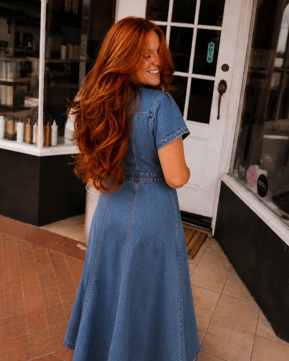 Woman with long copper red hair outside a salon